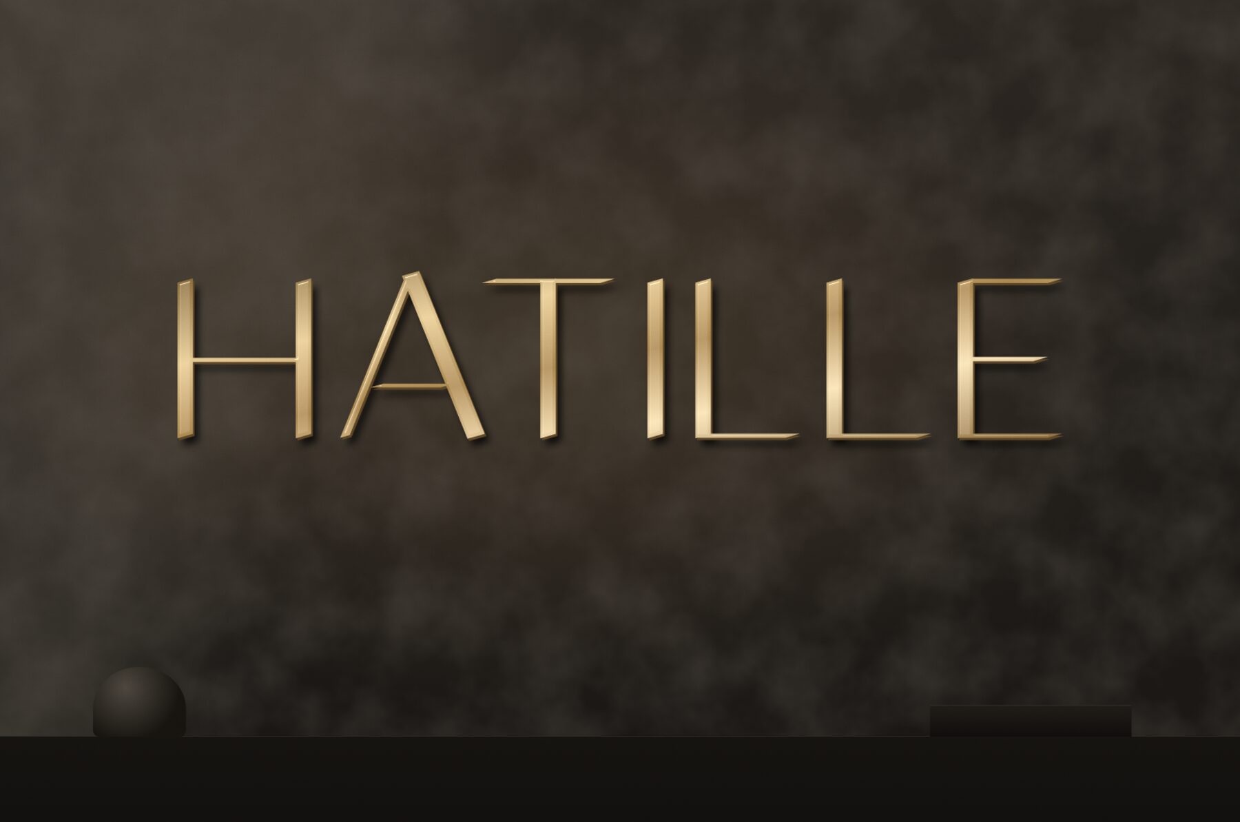 Hatille gold logo sign on a dark wall